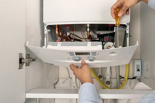 Heating technician repairing a residential boiler in Dana Point