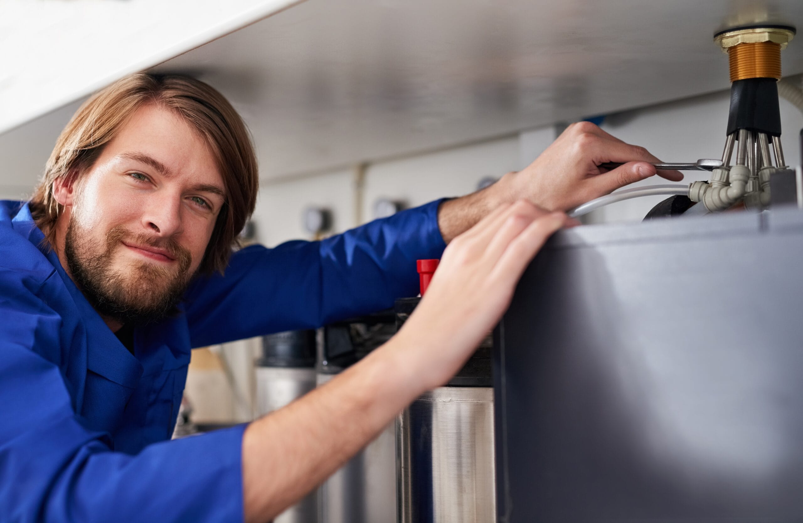 Technician servicing a residential water heater tank in Dana Point